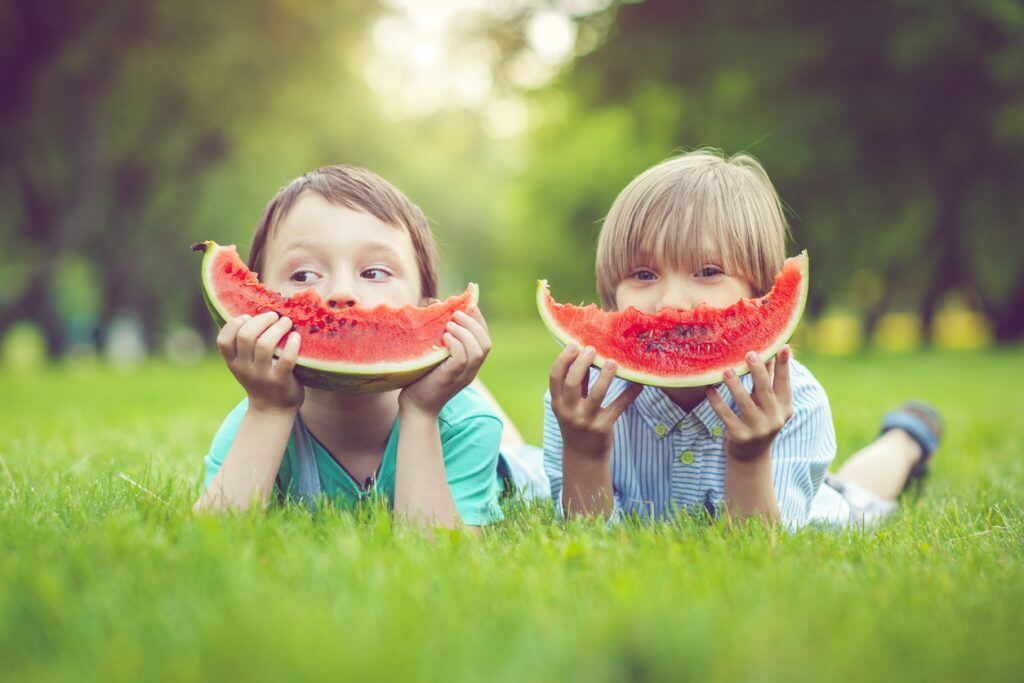 Two kids eating large watermelon slices | Motif