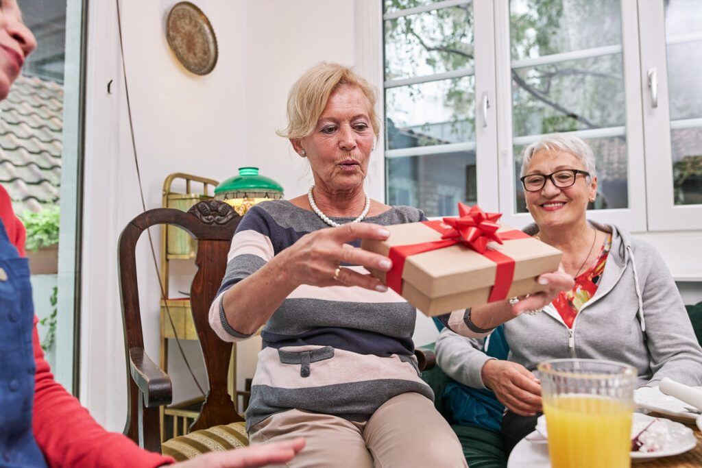 Cheerful and beautiful group of senior women enjoying time together on a home birthday party.