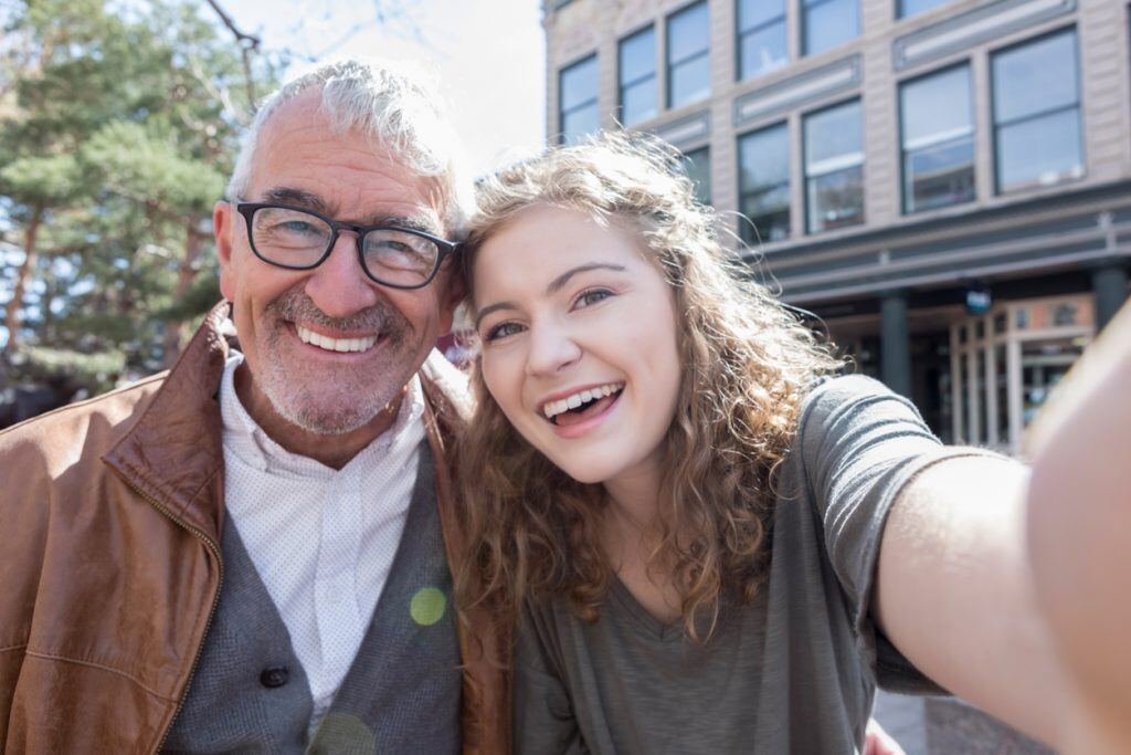 A girl taking a selfie with her grandfather | Motif