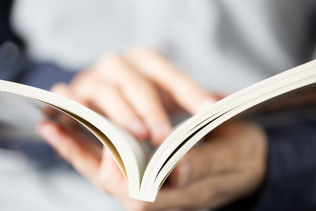 Close up shot of hands opening and reading book.