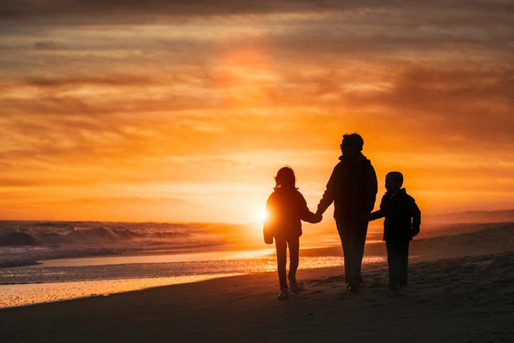 A silhouette of a family walking on the beach | Motif