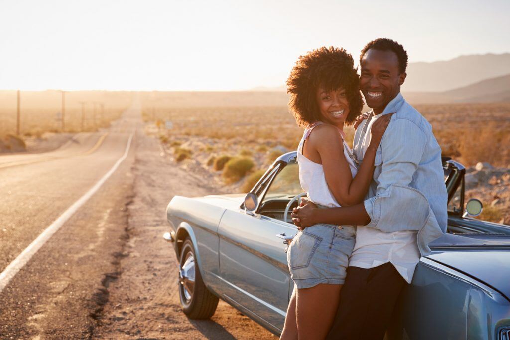 A couple hugging against a car during the golden hour | Motif