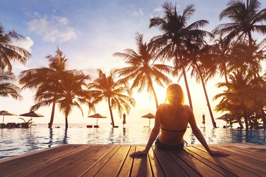 A girl sitting on the edge of a pool while the sun is setting | Motif