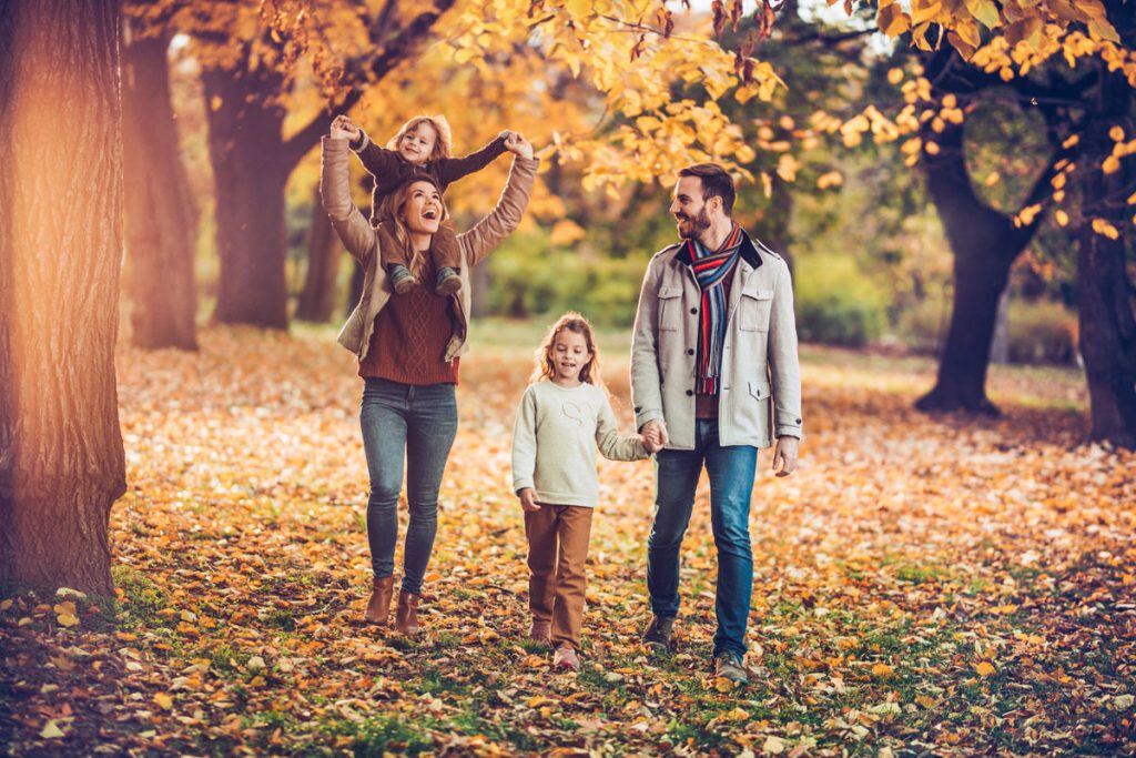 Family walking through fall trees during golden hour