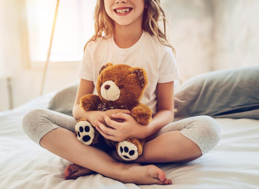 A girl sitting down with her teddy bear | Motif