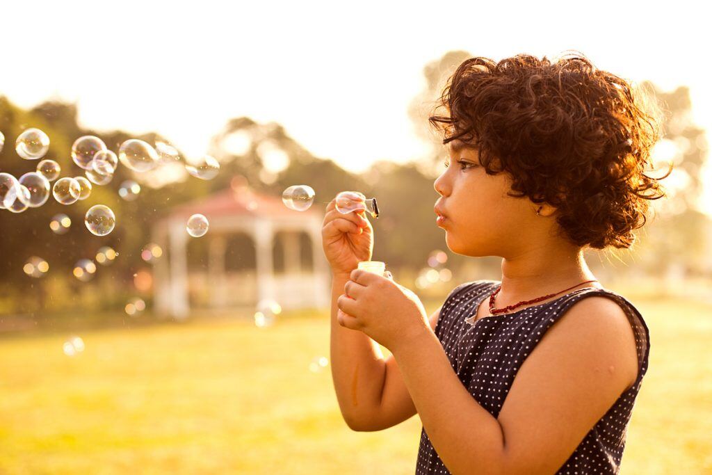 A girl blowing bubbles in a field | Motif