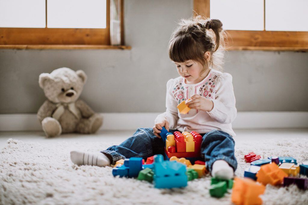 A girl playing with her toys on the ground | Motif