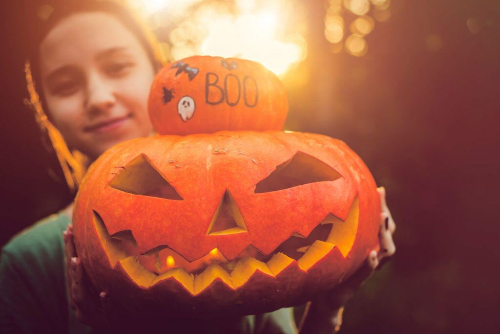 Girl holding up Jack-O-Lantern for the camera