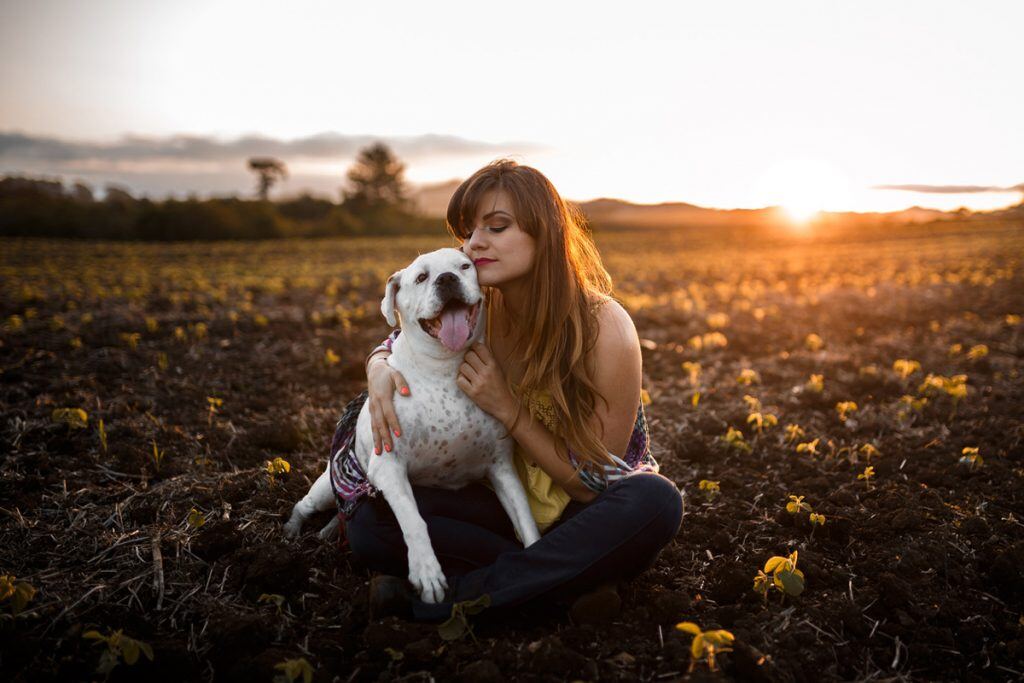 A girl and her dog sitting in a field at sunset | Motif