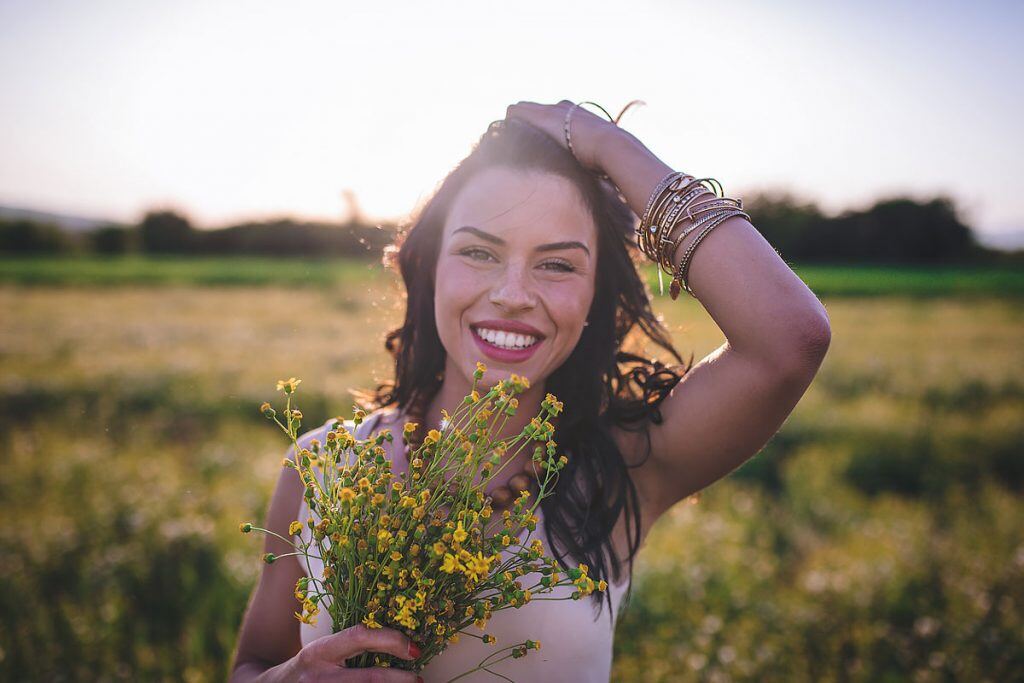 A portrait mode photo of a woman in a large field | Motif