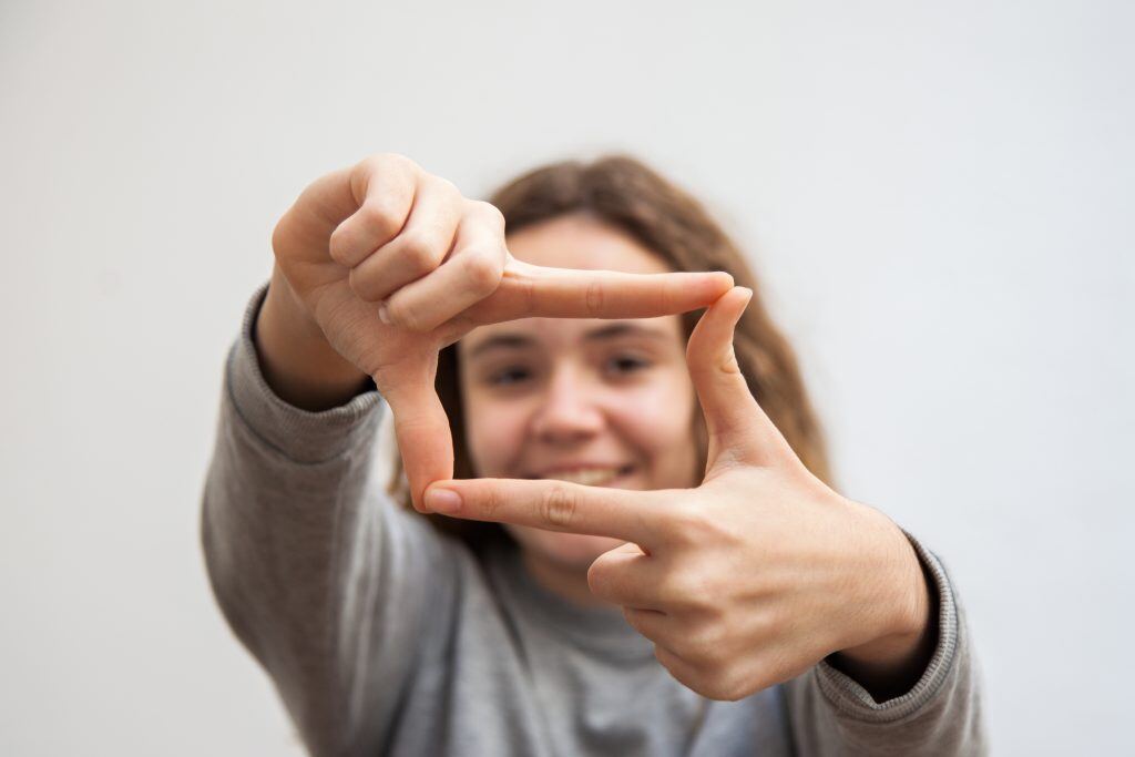 Girl frames her hands for a landscape photo, which may lead to a wider photo book size.