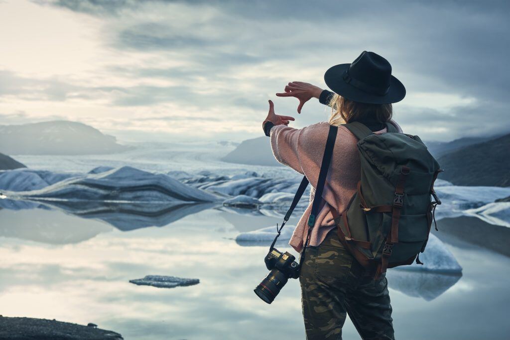 A photographer finds the focus of their glacier image using their two forefingers.