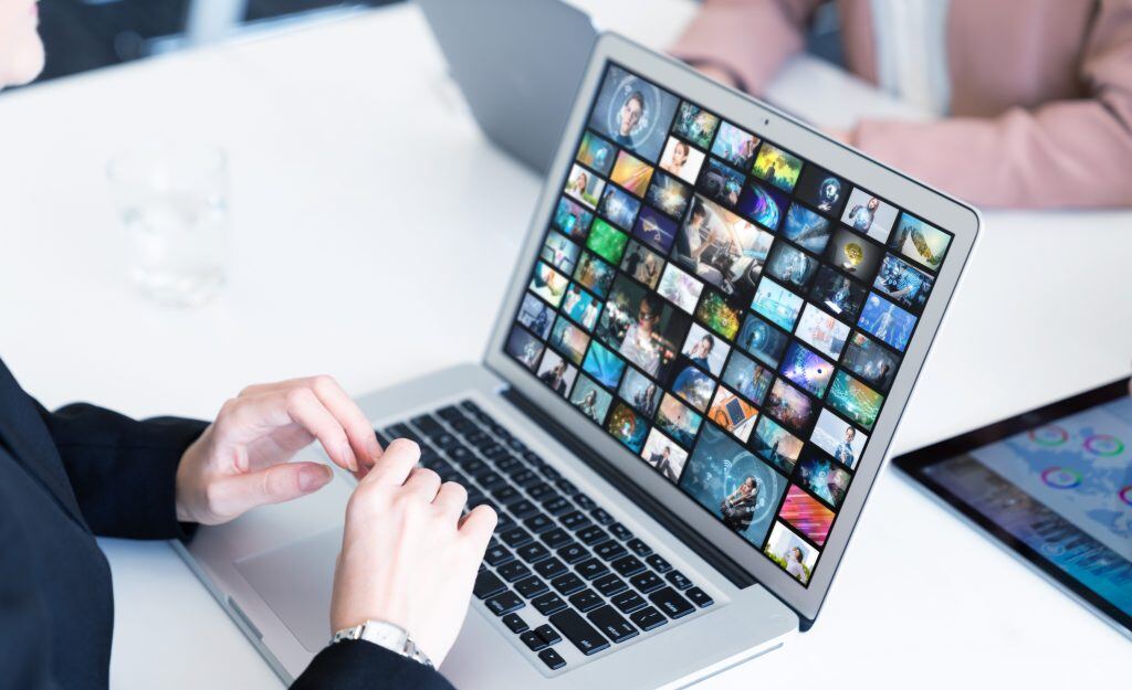 Woman prepares to organize photos on her Mac laptop at her desk.