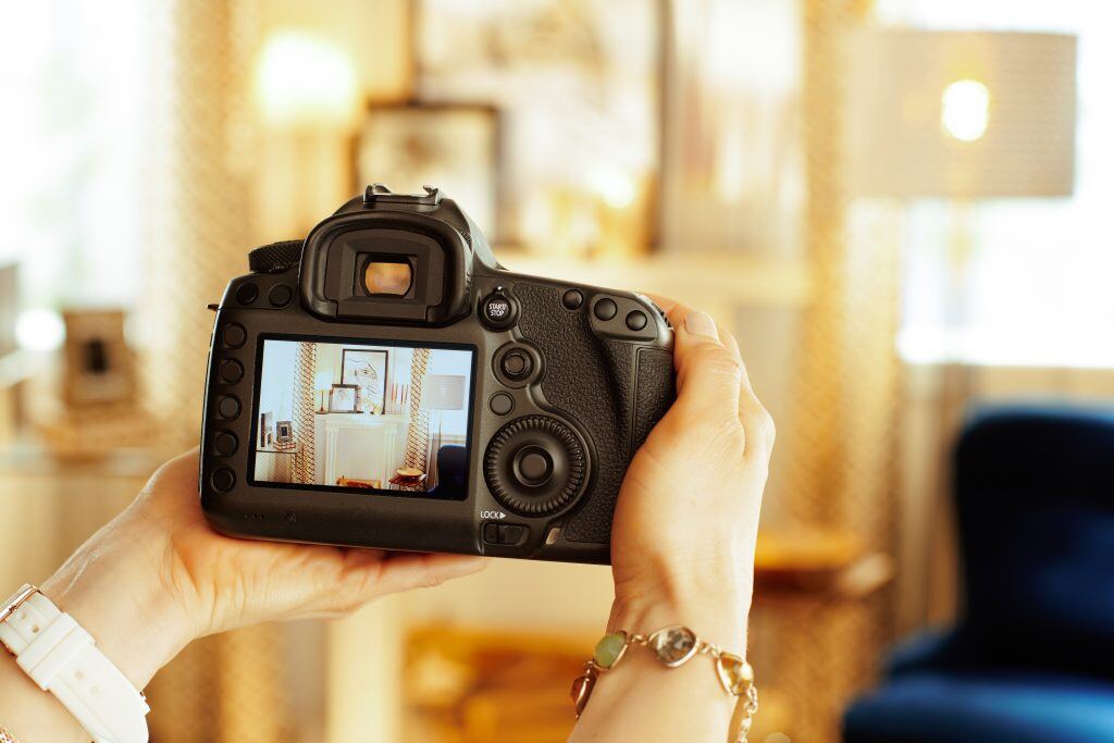 A woman holding a DSLR shows off the camera’s viewfinder.