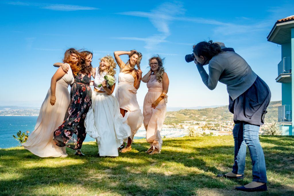 A wedding photographer captures a candid photo of the bride and bridesmaids laughing.