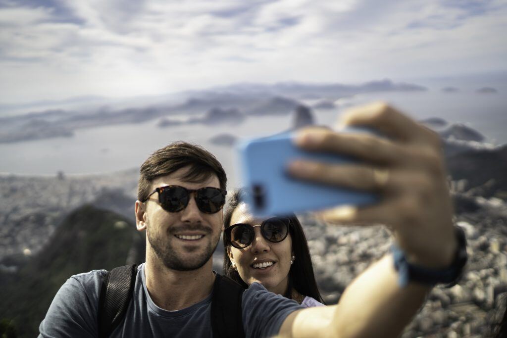 Young couple takes a selfie with iPhone, which automatically saves to digital photo storage.