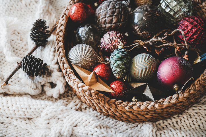 Christmas photography should include a collection of ornaments in wicker basket on knitted blanket.