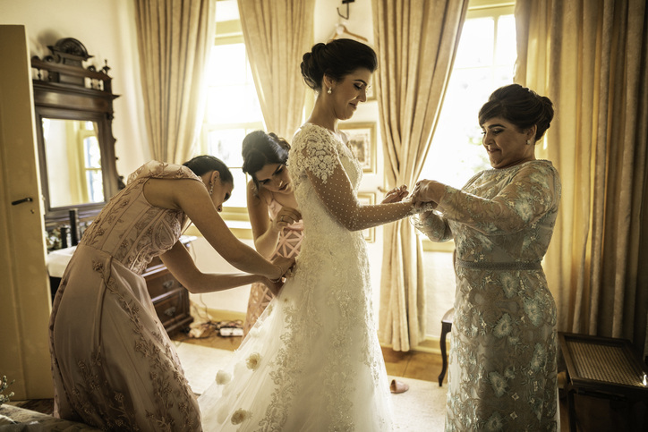 Classic wedding photos include helping the bride get dressed for her big day.