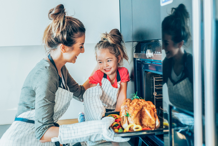 Little girl helps Mom pull turkey out of the oven, makes for a cute Thanksgiving photo card.