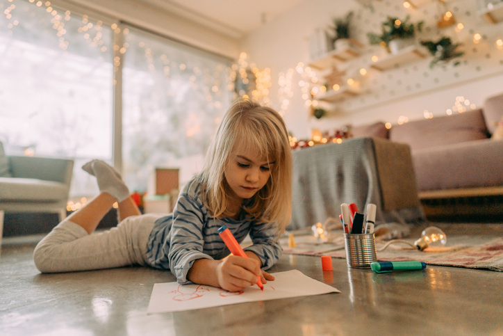 Little girl draws a picture by hand to make DIY Christmas cards this year.