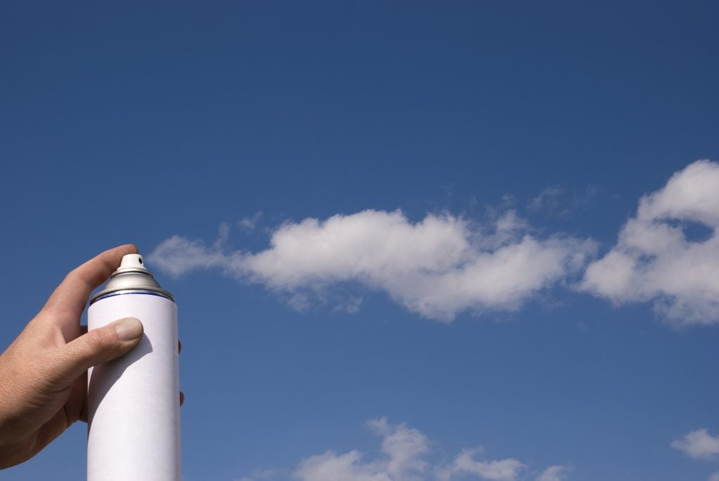 With forced perspective photography, a hand holding aerosol can looks like it’s spraying clouds.