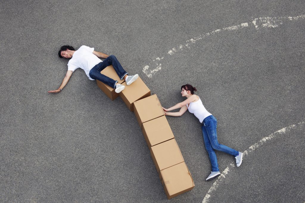 A forced perspective shot of a girl pushing a tower of boxes over.