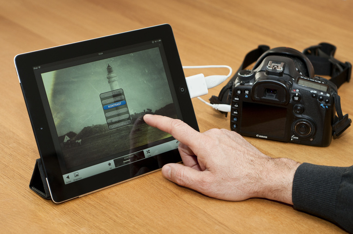 Man’s hands show how to connect DSLR to the iPad using adapter cords.