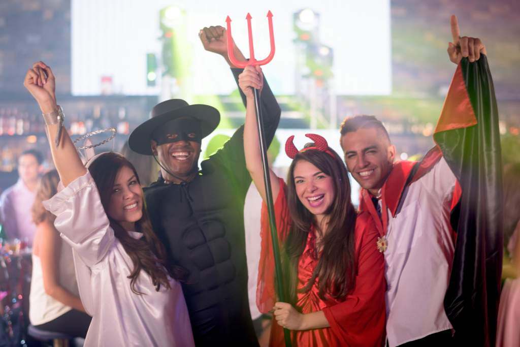 Two young couples take cute Halloween photos dressed as devils and angels.  