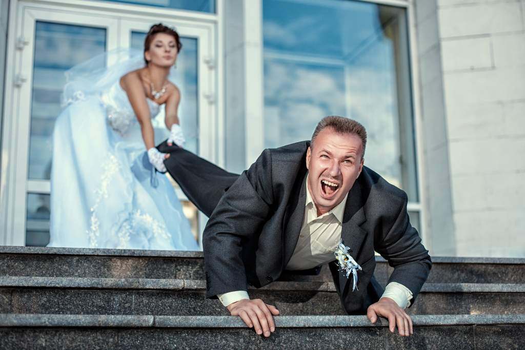 Funny poses for wedding pictures: bride pulls groom by the leg as he tries to crawl down stairs.