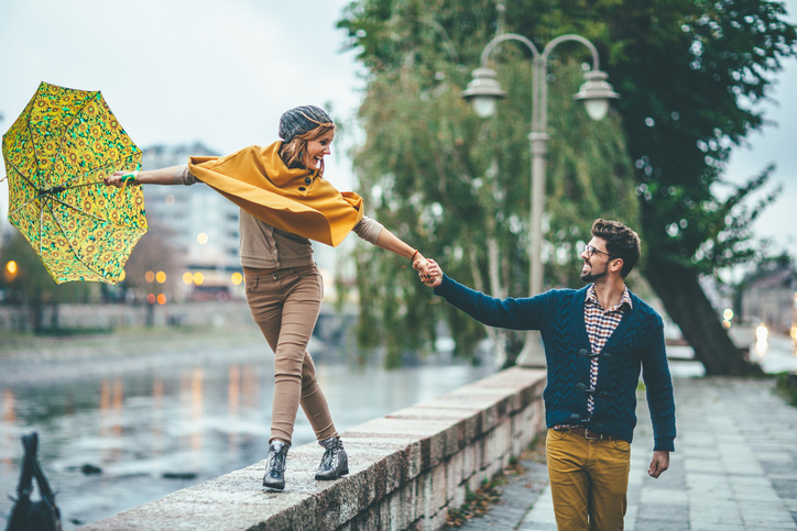 An engagement photo shoot in the rain can bring out the playful side of a couple.