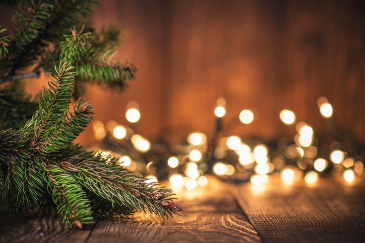 Christmas photography created by the base of a spruce tree and string lights with bokeh effect.