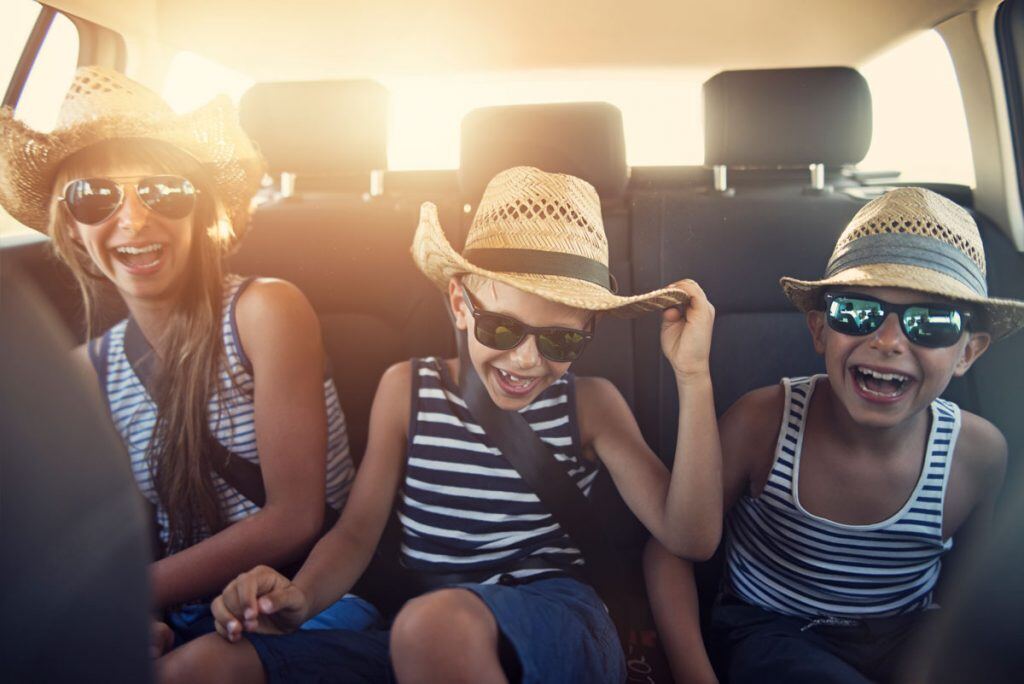 Three kids sitting in the back seat of a car | Motif