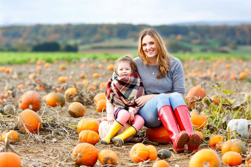 Mother and daughter sitting in a pumpkin patch