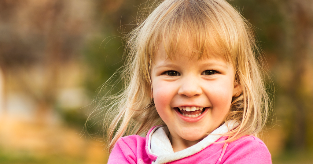 Selective focus means the viewer is meant to look at the smiling girl, not the background behind her.