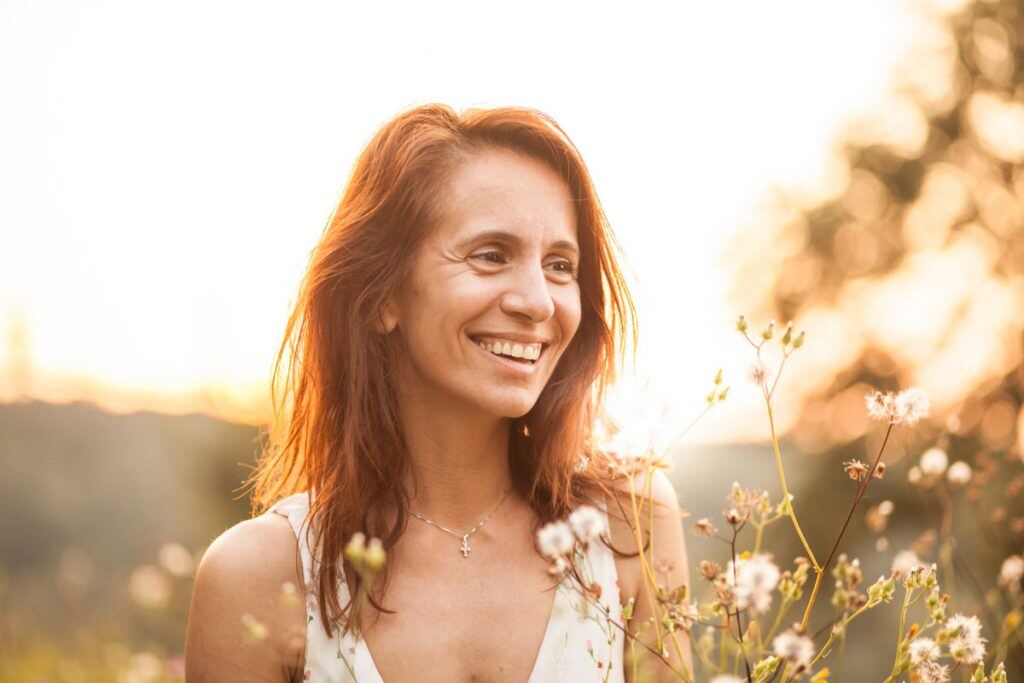 A woman posing for a picture in a field at sunset | Motif