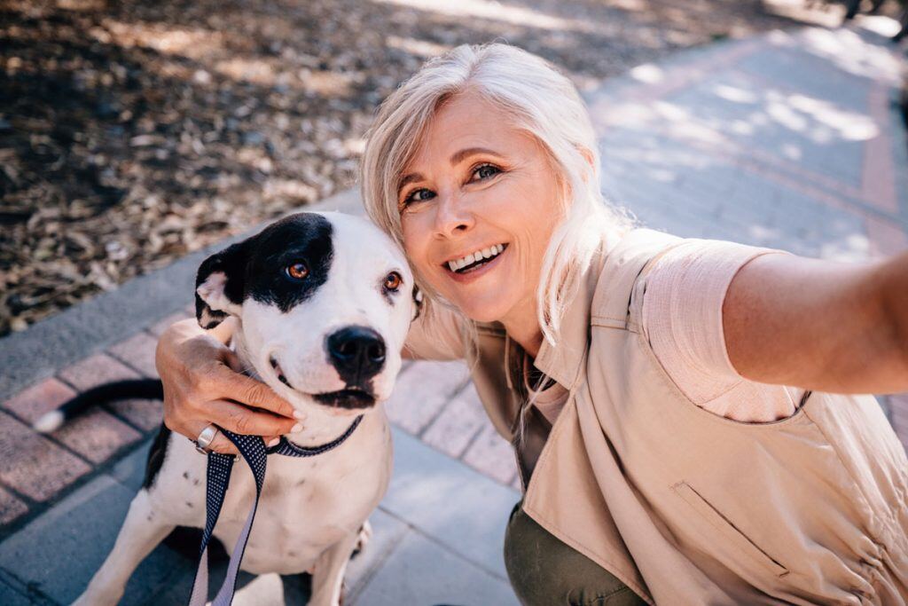 A woman taking a selfie with her dog | Motif