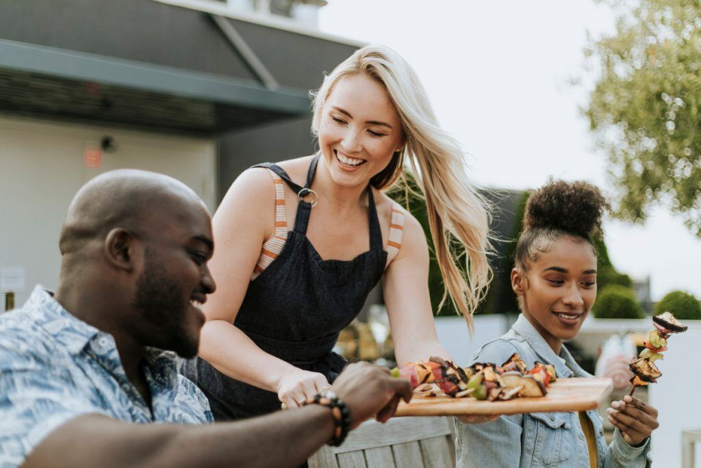 Serving up barbeque skewers at a summer dinner party