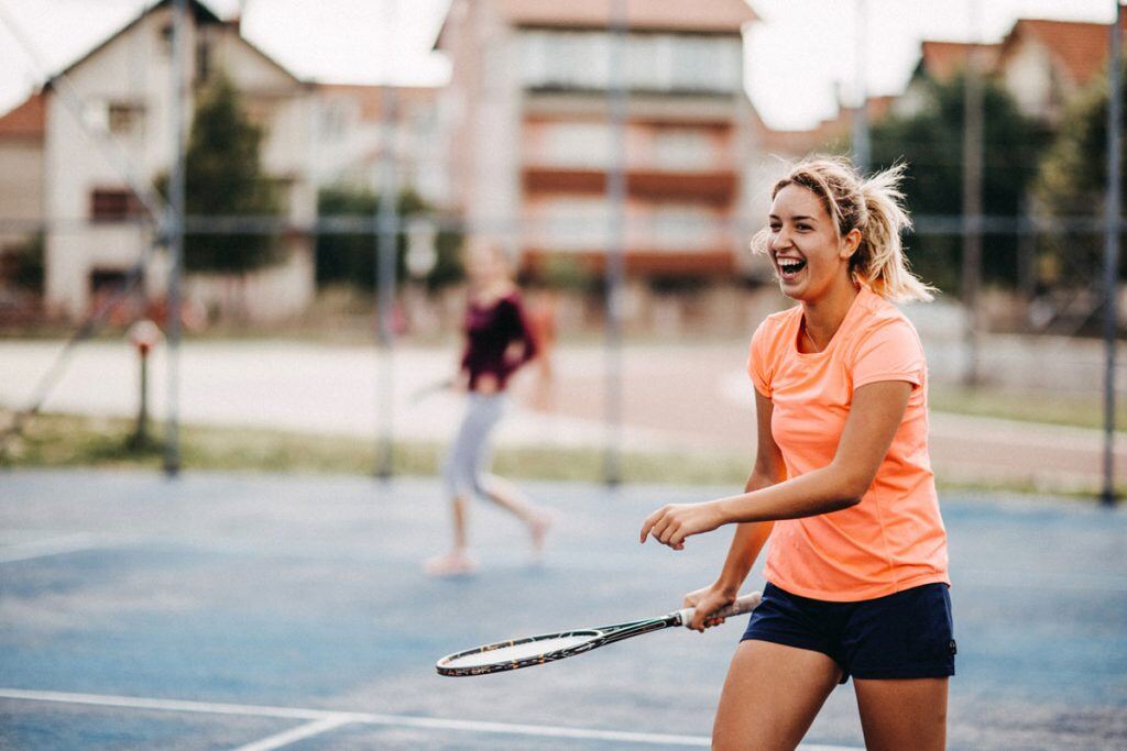 A portrait mode photo of two girls playing tennis | Motif